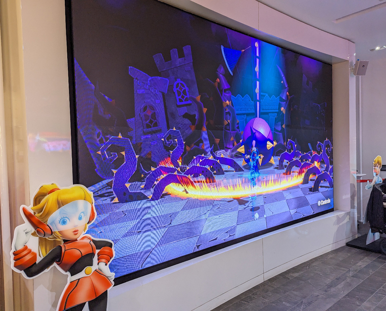 Mighty Peach cheers on players as they attempt the demo on a giant screen